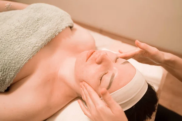 Mooie jonge vrouw het krijgen van een gezicht massage behandeling bij schoonheid salon — Stockfoto