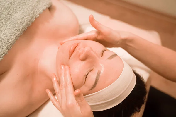 Hermosa joven recibiendo un tratamiento de masaje facial en el salón de belleza —  Fotos de Stock