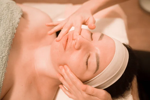 Hermosa joven recibiendo un tratamiento de masaje facial en el salón de belleza —  Fotos de Stock