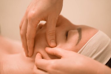 Güzel genç bir kadın güzellik salonunda yüz masajı yaptırıyor.