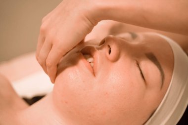 Güzel genç bir kadın güzellik salonunda yüz masajı yaptırıyor.