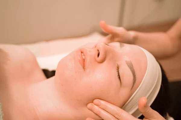 Hermosa joven recibiendo un tratamiento de masaje facial en el salón de belleza — Foto de Stock