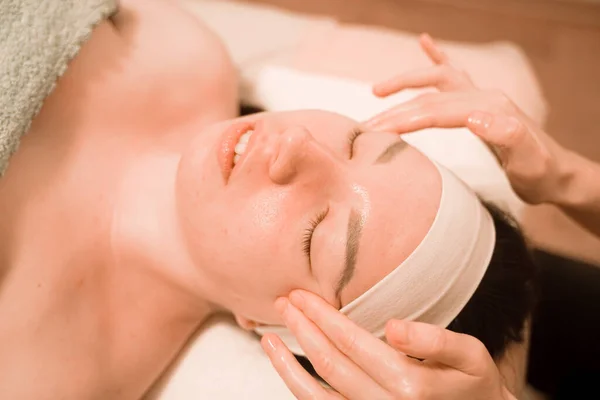 Hermosa joven recibiendo un tratamiento de masaje facial en el salón de belleza — Foto de Stock