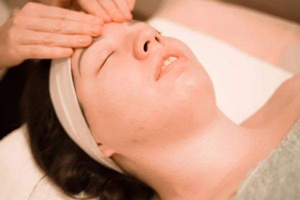 Hermosa joven recibiendo un tratamiento de masaje facial en el salón de belleza — Foto de Stock