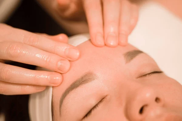 Beautiful young woman getting a face massage treatment at beauty salon — Stock Photo, Image