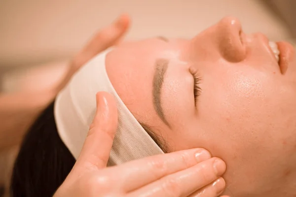 Hermosa joven recibiendo un tratamiento de masaje facial en el salón de belleza — Foto de Stock