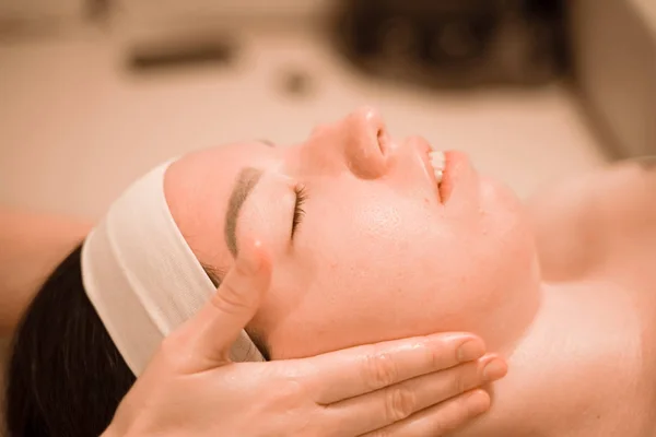 Hermosa joven recibiendo un tratamiento de masaje facial en el salón de belleza —  Fotos de Stock