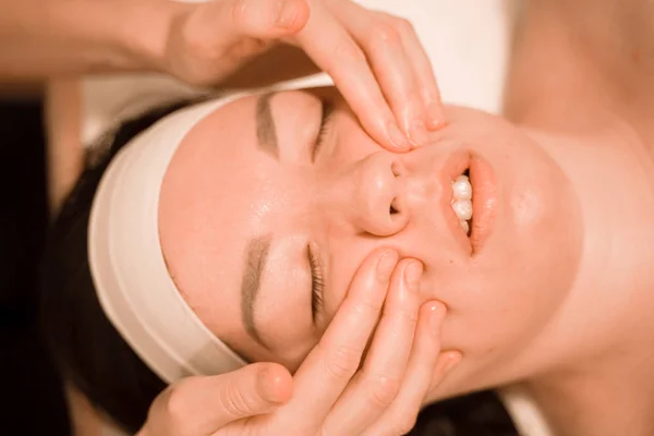 Vacker ung kvinna att få en ansiktsmassage behandling på skönhetssalong — Stockfoto