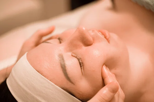 Hermosa joven recibiendo un tratamiento de masaje facial en el salón de belleza —  Fotos de Stock