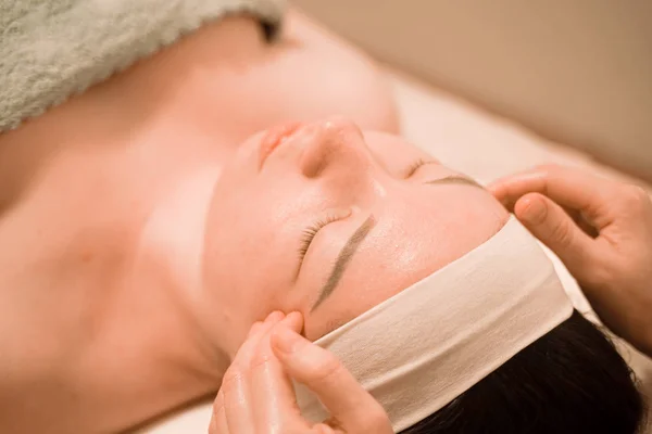Güzel genç bir kadın güzellik salonunda yüz masajı yaptırıyor. — Stok fotoğraf