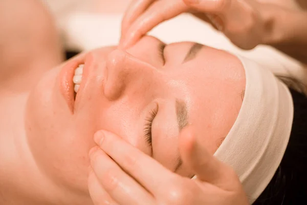 Hermosa joven recibiendo un tratamiento de masaje facial en el salón de belleza —  Fotos de Stock