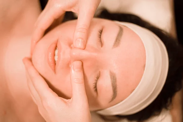 Hermosa joven recibiendo un tratamiento de masaje facial en el salón de belleza paso a paso — Foto de Stock