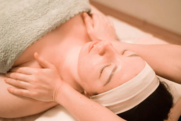 Hermosa joven recibiendo un tratamiento de masaje facial en el salón de belleza — Foto de Stock