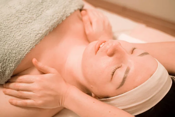 Hermosa joven recibiendo un tratamiento de masaje facial en el salón de belleza —  Fotos de Stock