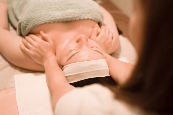 Hermosa joven recibiendo un tratamiento de masaje facial en el salón de belleza —  Fotos de Stock