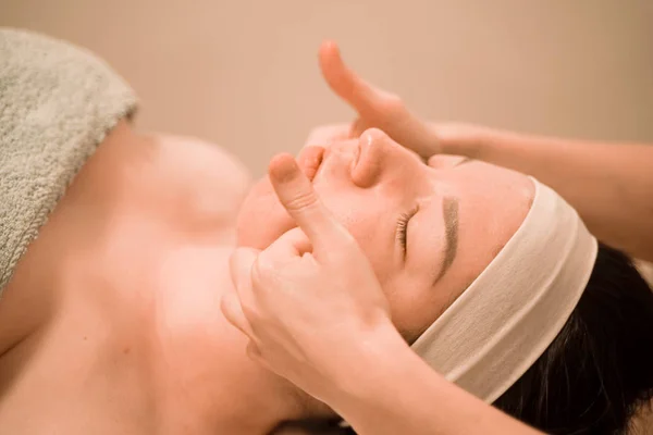 Piękna młoda kobieta otrzymuje masaż twarzy w salonie piękności — Zdjęcie stockowe