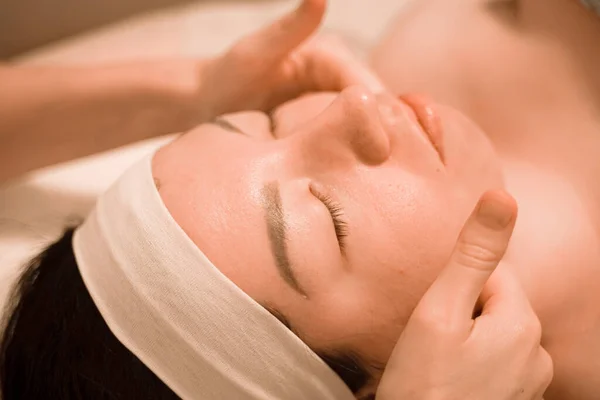 Hermosa joven recibiendo un tratamiento de masaje facial en el salón de belleza —  Fotos de Stock