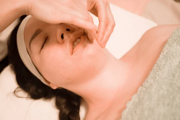 Hermosa joven recibiendo un tratamiento de masaje facial en el salón de belleza — Foto de Stock