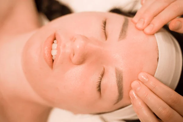 Hermosa joven recibiendo un tratamiento de masaje facial en el salón de belleza — Foto de Stock