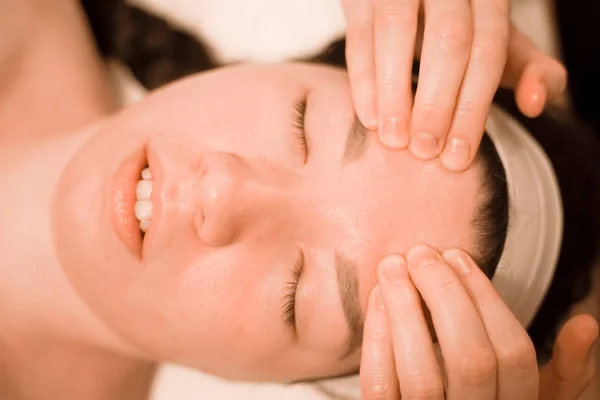 Hermosa joven recibiendo un tratamiento de masaje facial en el salón de belleza —  Fotos de Stock
