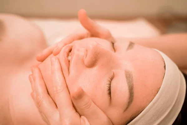 Hermosa joven recibiendo un tratamiento de masaje facial en el salón de belleza — Foto de Stock