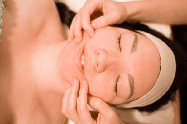 Hermosa joven recibiendo un tratamiento de masaje facial en el salón de belleza — Foto de Stock