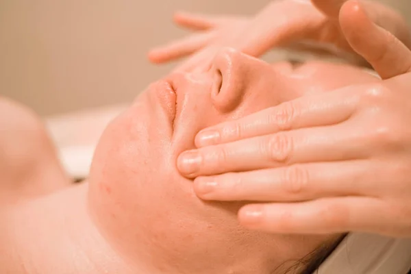 Hermosa joven recibiendo un tratamiento de masaje facial en el salón de belleza — Foto de Stock