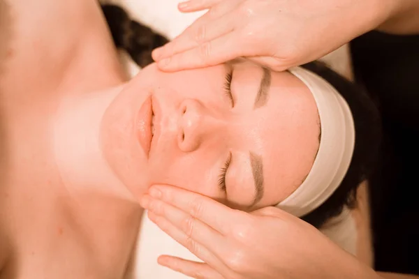 Hermosa joven recibiendo un tratamiento de masaje facial en el salón de belleza — Foto de Stock