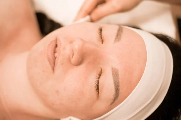 Portrait of young woman washing her face with cotton pad, close up in the spa salon — Stock Photo, Image