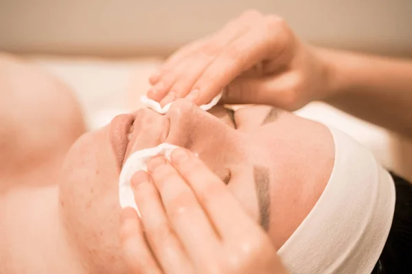 Portrait of young woman washing her face with cotton pad, close up in the spa salon — Stock Photo, Image