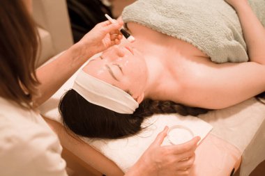 Şirin bir melez kadın yalan söylüyor ve yüzüne fırça maskesi takmaktan zevk alıyor.