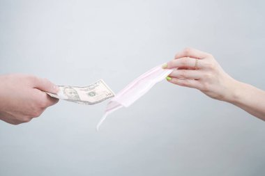Tıbbi maskeler hakkında spekülasyonlar. İnsanlar çok pahalı maskeler satıyorlar, çünkü onlardan yeterince yok. Maskeyi ve parayı birbirlerine uzatırlar. düz beyaz stüdyo arkaplanı