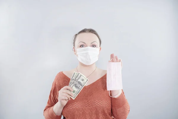 Price gouging during shortage of virus masks. The speculator sells medical masks very expensive. Pile of anti virus surgical face masks and money. Concept.