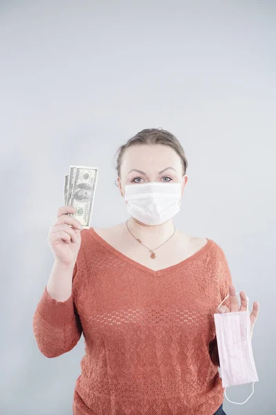 Price gouging during shortage of virus masks. The speculator sells medical masks very expensive. Pile of anti virus surgical face masks and money. Concept.