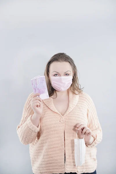 Middle age woman on white background. People try to buy medical masks during the quarantine period for any money. The concept of speculation in the market of necessary products. Covid epidemic