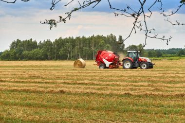 Biale, Polonya - 04 Ağustos 2017: Traktör sahada çalışıyor. Saman ve buğday alanında yaz sonu Polonya, saman yığını
