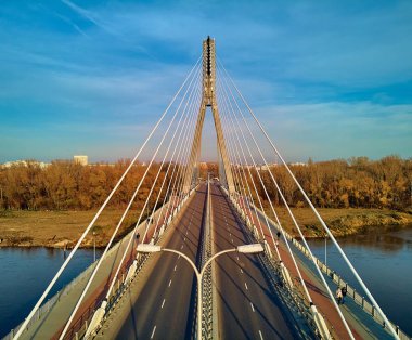 Beautiful panoramic aerial dsrone view to Swietokrzyski Bridge (English: Holy Cross Bridge) - is a cable-stayed bridge over the Vistula river in Warsaw, Poland in autumn November evening at sunset clipart