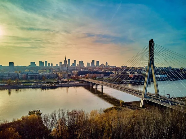 Schöne Panorama-Drohne Sonnenuntergang Blick auf die Warschauer Innenstadt mit Wolkenkratzern und Swietokrzyski-Brücke (de: Heilig-Kreuz-Brücke) - ist eine Schrägseilbrücke über den Weichsel-Fluss in Warschau, Polen — Stockfoto