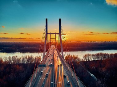 Vistula nehri ve Varşova şehri gökdelenleri üzerindeki Siekierkowski Köprüsü 'ne güzel panoramik hava aracı görüntüsü Kasım akşamı günbatımında Polonya' nın altın kırmızısı sonbahar renklerinde.