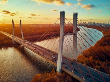 Vistula nehri ve Varşova şehri gökdelenleri üzerindeki Siekierkowski Köprüsü 'ne güzel panoramik hava aracı görüntüsü Kasım akşamı günbatımında Polonya' nın altın kırmızısı sonbahar renklerinde.