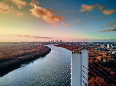 Vistula nehri ve Varşova şehri gökdelenleri üzerindeki Siekierkowski Köprüsü 'ne güzel panoramik hava aracı görüntüsü Kasım akşamı günbatımında Polonya' nın altın kırmızısı sonbahar renklerinde.