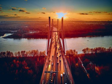 Vistula nehri ve Varşova şehri gökdelenleri üzerindeki Siekierkowski Köprüsü 'ne güzel panoramik hava aracı görüntüsü Kasım akşamı günbatımında Polonya' nın altın kırmızısı sonbahar renklerinde.