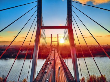 Vistula nehri ve Varşova şehri gökdelenleri üzerindeki Siekierkowski Köprüsü 'ne güzel panoramik hava aracı görüntüsü Kasım akşamı günbatımında Polonya' nın altın kırmızısı sonbahar renklerinde.