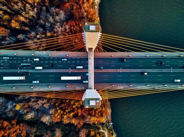 Beautiful panoramic aerial drone view to cable-stayed Siekierkowski Bridge over the Vistula river and Warsaw City skyscrapers, Poland in gold red autumn colors in November evening at sunset - top down clipart