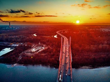 Vistula nehri ve Varşova şehri gökdelenleri üzerindeki Siekierkowski Köprüsü 'ne güzel panoramik hava aracı görüntüsü Kasım akşamı günbatımında Polonya' nın altın kırmızısı sonbahar renklerinde.