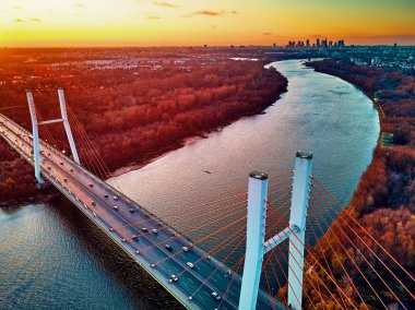 Vistula nehri ve Varşova şehri gökdelenleri üzerindeki Siekierkowski Köprüsü 'ne güzel panoramik hava aracı görüntüsü Kasım akşamı günbatımında Polonya' nın altın kırmızısı sonbahar renklerinde.