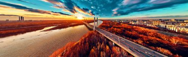 Vistula nehri ve Varşova şehri gökdelenleri üzerindeki Siekierkowski Köprüsü 'ne güzel panoramik hava aracı görüntüsü Kasım akşamı günbatımında Polonya' nın altın kırmızısı sonbahar renklerinde.