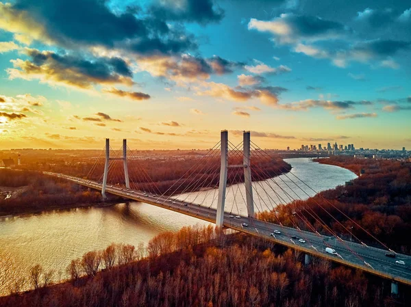 Hermosa vista panorámica del dron aéreo al puente de Siekierkowski por cable sobre el río Vístula y los rascacielos de la ciudad de Varsovia, Polonia en colores dorados de otoño rojo en la noche de noviembre al atardecer — Foto de Stock