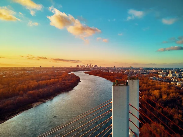 Hermosa vista panorámica del dron aéreo al puente de Siekierkowski por cable sobre el río Vístula y los rascacielos de la ciudad de Varsovia, Polonia en colores dorados de otoño rojo en la noche de noviembre al atardecer — Foto de Stock