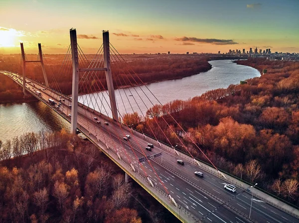 Bela vista panorâmica de drones aéreos para a ponte Siekierkowski sobre o rio Vístula e arranha-céus da cidade de Varsóvia, na Polônia, em cores vermelhas douradas do outono, em novembro à noite, ao pôr do sol — Fotografia de Stock